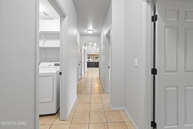 hall featuring washer / dryer and light tile patterned floors