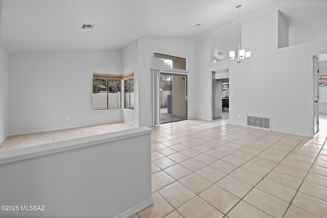 spare room featuring a chandelier, light tile patterned floors, and high vaulted ceiling