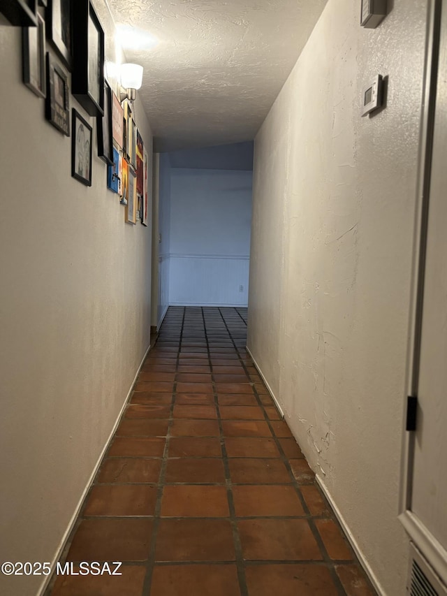 hall featuring dark tile patterned floors and a textured ceiling