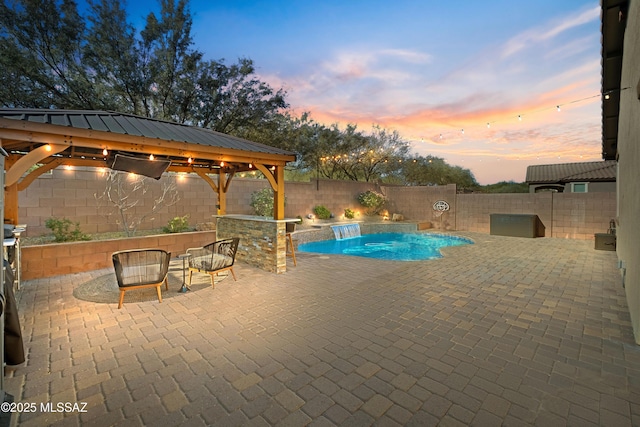 pool at dusk with a gazebo and a patio