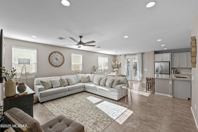 living room with french doors, ceiling fan with notable chandelier, plenty of natural light, and sink