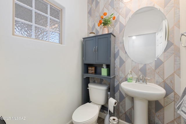 bathroom featuring toilet, tile walls, and sink