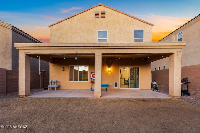 back house at dusk featuring a patio area