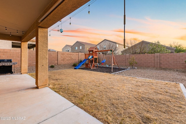 yard at dusk featuring a patio and a playground