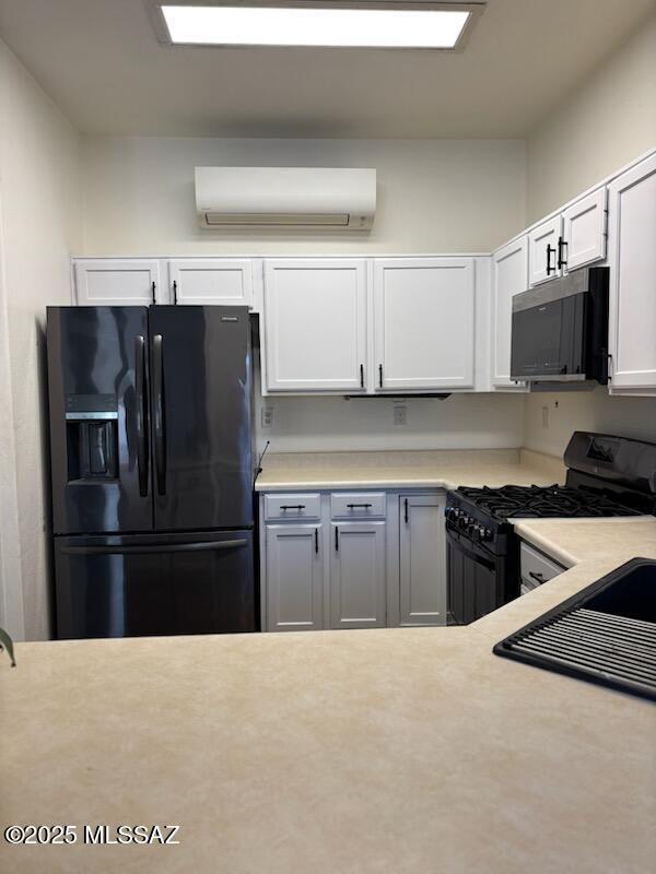 kitchen featuring black appliances, white cabinets, and a wall mounted AC