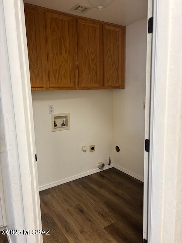 clothes washing area featuring cabinets, hookup for a washing machine, electric dryer hookup, dark hardwood / wood-style floors, and hookup for a gas dryer