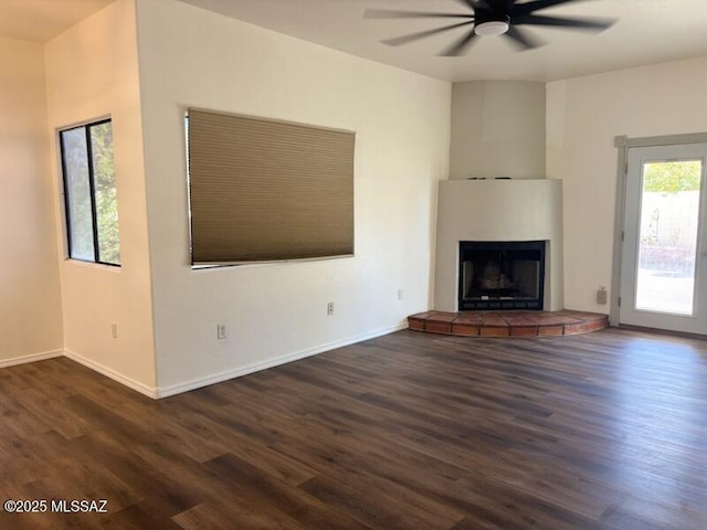 unfurnished living room featuring dark hardwood / wood-style floors, ceiling fan, and a tiled fireplace