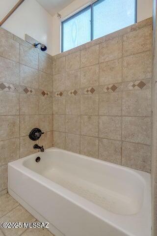 bathroom featuring tile patterned flooring and tiled shower / bath