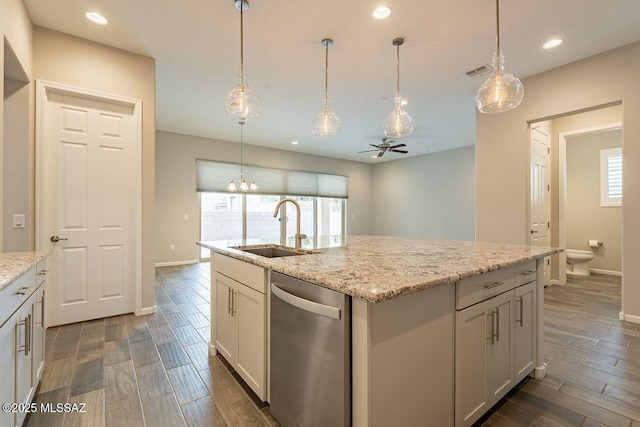 kitchen with stainless steel dishwasher, white cabinets, sink, and a center island with sink