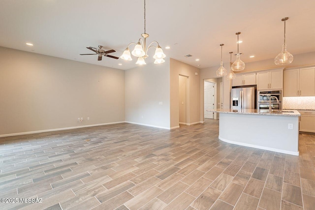 kitchen featuring white cabinetry, an island with sink, appliances with stainless steel finishes, decorative backsplash, and pendant lighting