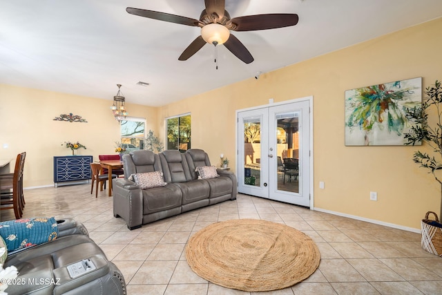 living room featuring ceiling fan with notable chandelier, light tile patterned floors, and french doors