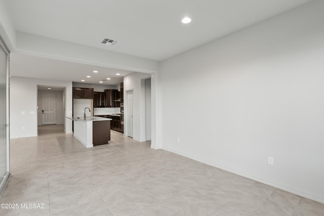 unfurnished living room featuring light tile patterned floors and sink