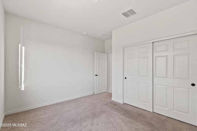 unfurnished bedroom with light colored carpet and a closet