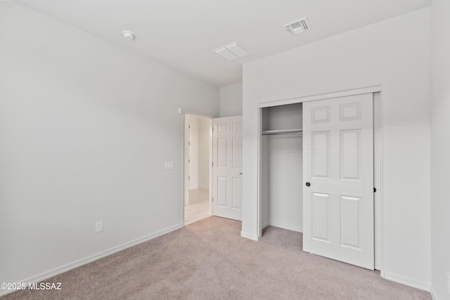 unfurnished bedroom featuring light carpet and a closet