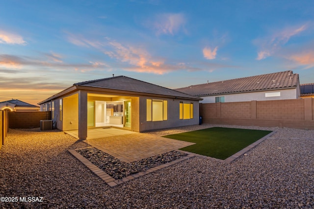 back house at dusk featuring a patio and central AC unit