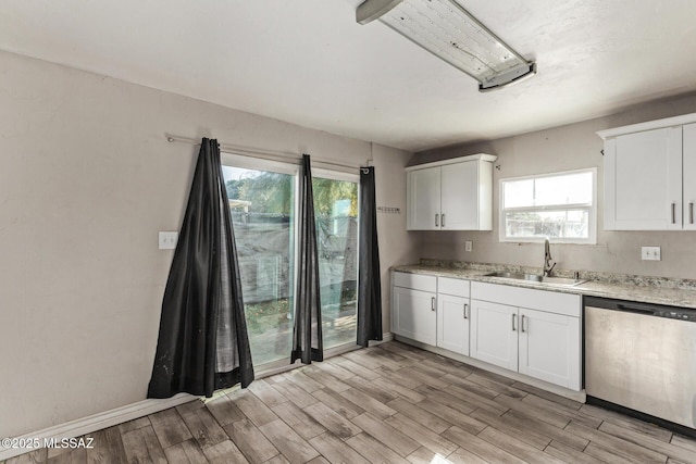 kitchen with white cabinets, sink, stainless steel dishwasher, light hardwood / wood-style floors, and light stone counters