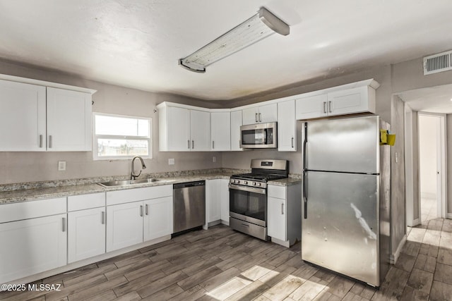 kitchen with hardwood / wood-style floors, white cabinetry, sink, and stainless steel appliances