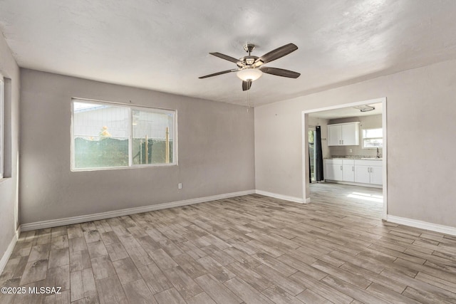 unfurnished room featuring ceiling fan, light wood-type flooring, and sink