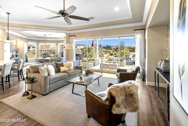 living room featuring hardwood / wood-style flooring, ceiling fan, ornamental molding, and a tray ceiling