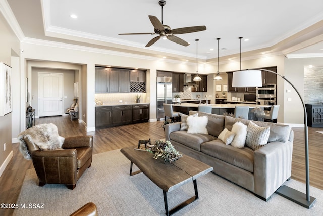 living room with light wood-type flooring, ceiling fan, and ornamental molding