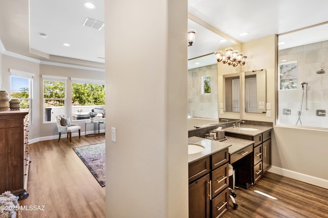 bathroom featuring an inviting chandelier, a shower, hardwood / wood-style floors, a tray ceiling, and vanity