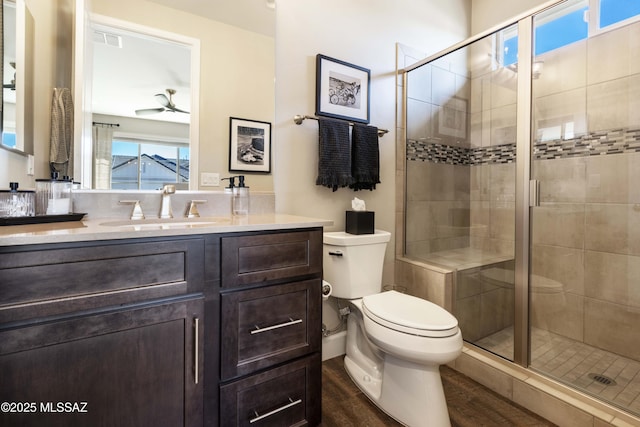 bathroom with ceiling fan, hardwood / wood-style floors, a shower with door, and toilet