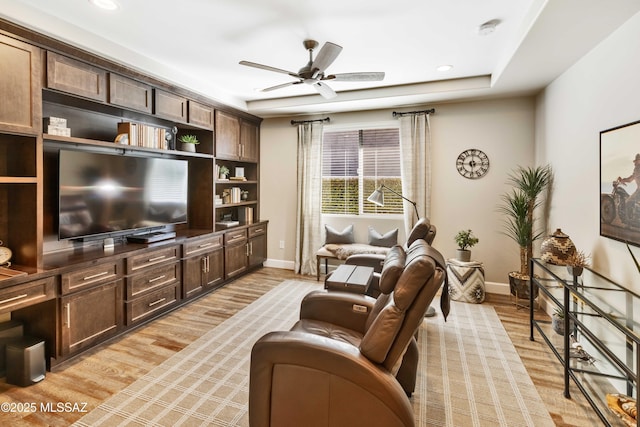 interior space with ceiling fan, a raised ceiling, and light hardwood / wood-style flooring