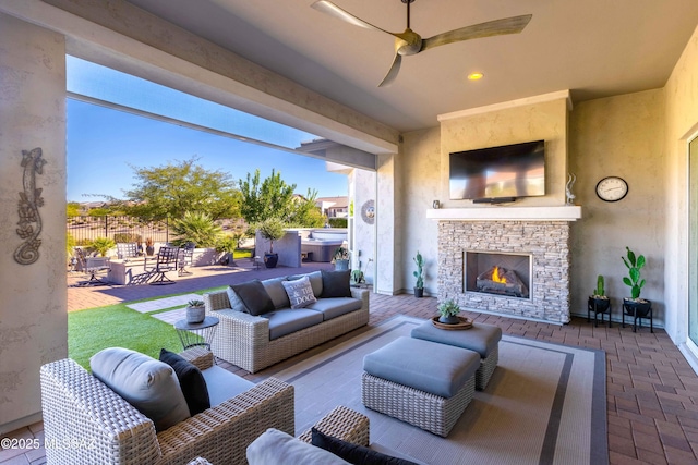 view of patio with an outdoor living space with a fireplace and ceiling fan