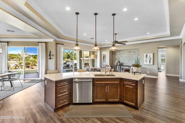 kitchen with dishwasher, a center island with sink, a raised ceiling, and sink