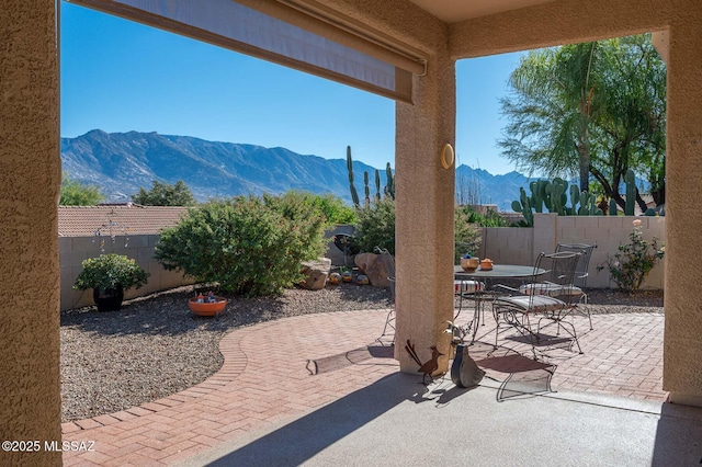 view of patio / terrace with outdoor dining area, a fenced backyard, and a mountain view