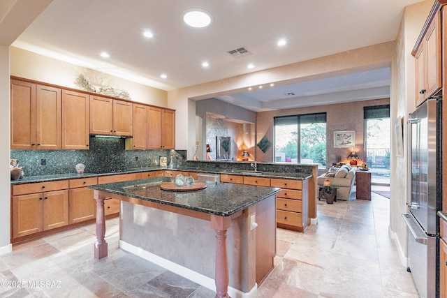 kitchen featuring a breakfast bar area, dark stone countertops, sink, and a kitchen island