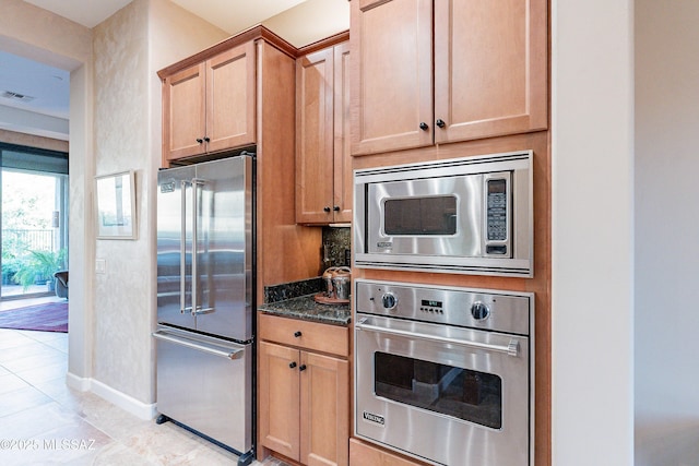 kitchen featuring appliances with stainless steel finishes and dark stone counters