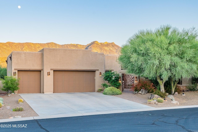 pueblo-style house featuring a mountain view and a garage