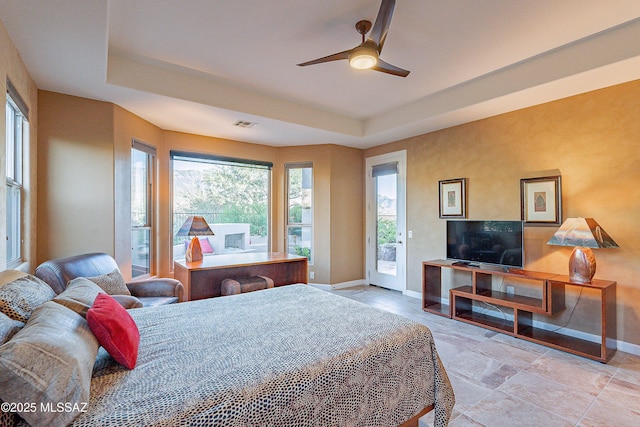 bedroom with a tray ceiling, access to exterior, and ceiling fan