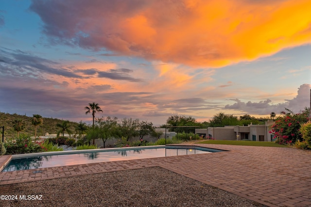 pool at dusk featuring a patio area