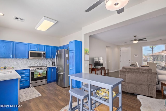 kitchen with appliances with stainless steel finishes, tasteful backsplash, blue cabinets, sink, and dark hardwood / wood-style floors