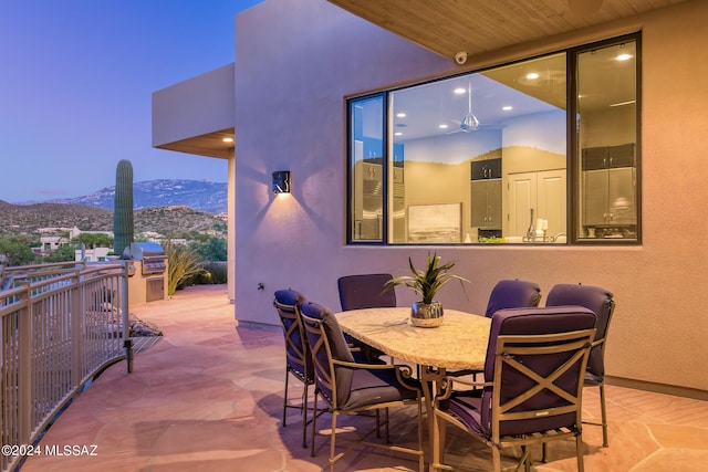 patio terrace at dusk with a mountain view, an outdoor kitchen, and grilling area