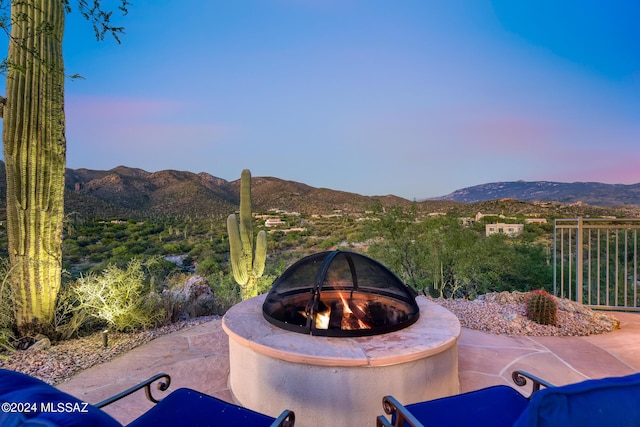 patio terrace at dusk featuring a mountain view and an outdoor fire pit