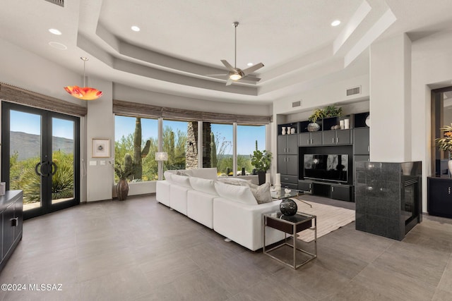 living room featuring a mountain view, french doors, a raised ceiling, ceiling fan, and dark tile patterned floors