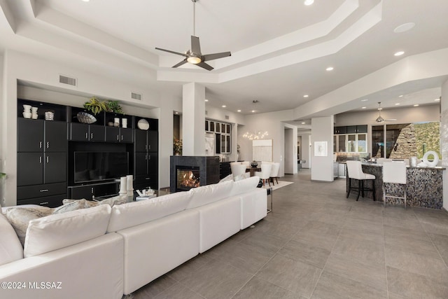 living room with ceiling fan and a raised ceiling