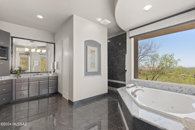 bathroom featuring vanity, a relaxing tiled tub, and a wealth of natural light