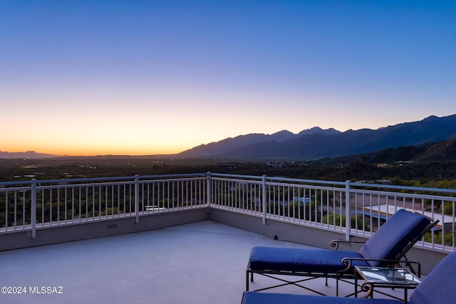 patio terrace at dusk featuring a mountain view and a balcony