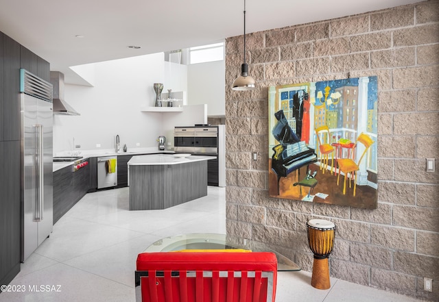 kitchen featuring a center island, sink, wall chimney exhaust hood, appliances with stainless steel finishes, and decorative light fixtures