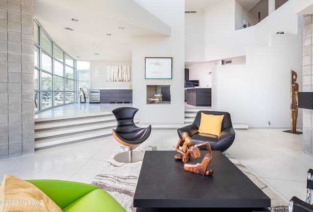 living room featuring a tiled fireplace and a high ceiling