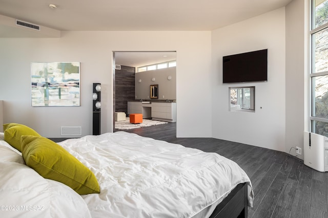 bedroom featuring multiple windows, ensuite bathroom, and dark hardwood / wood-style floors