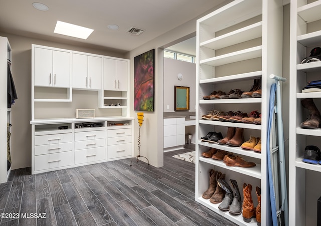 spacious closet with dark hardwood / wood-style flooring and a skylight