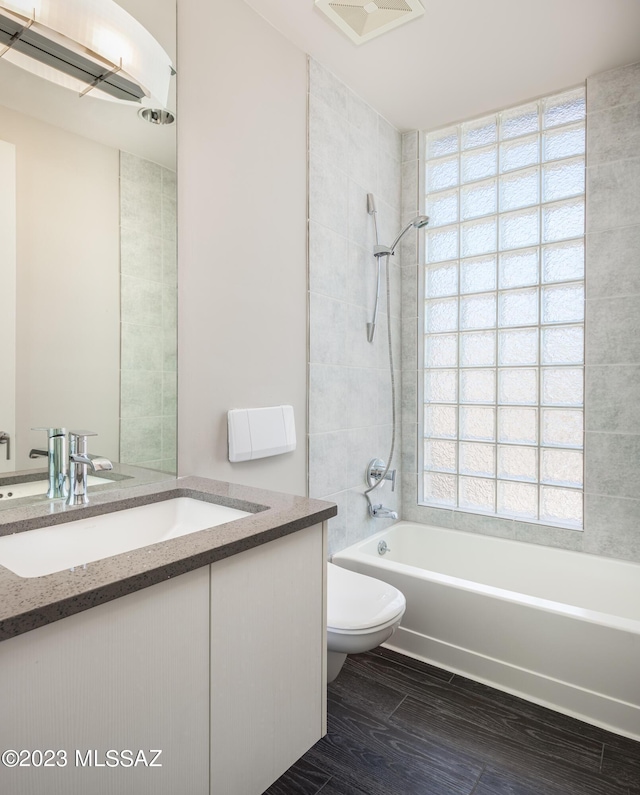 full bathroom with vanity, a healthy amount of sunlight, tiled shower / bath combo, and toilet