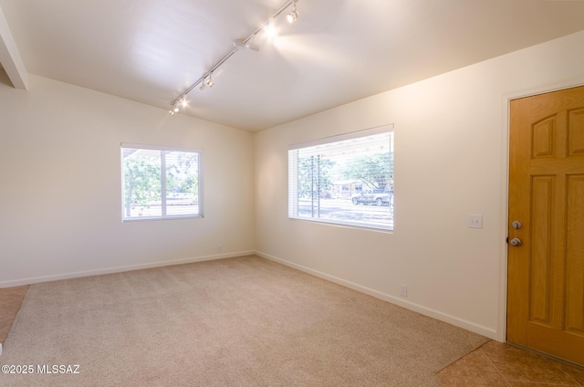 unfurnished room featuring rail lighting, light colored carpet, and lofted ceiling