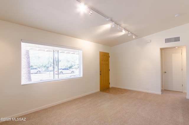 carpeted empty room featuring track lighting