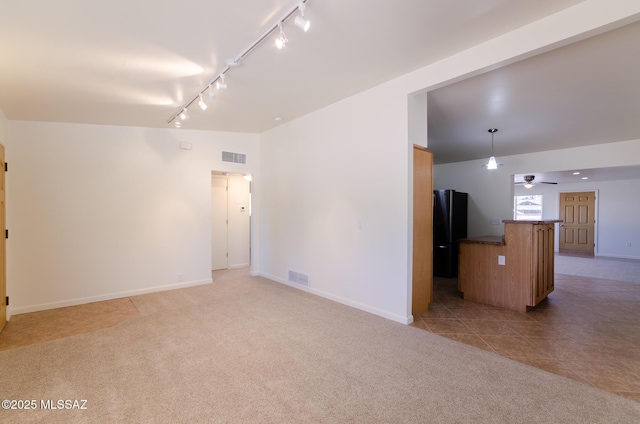 carpeted empty room with rail lighting and ceiling fan